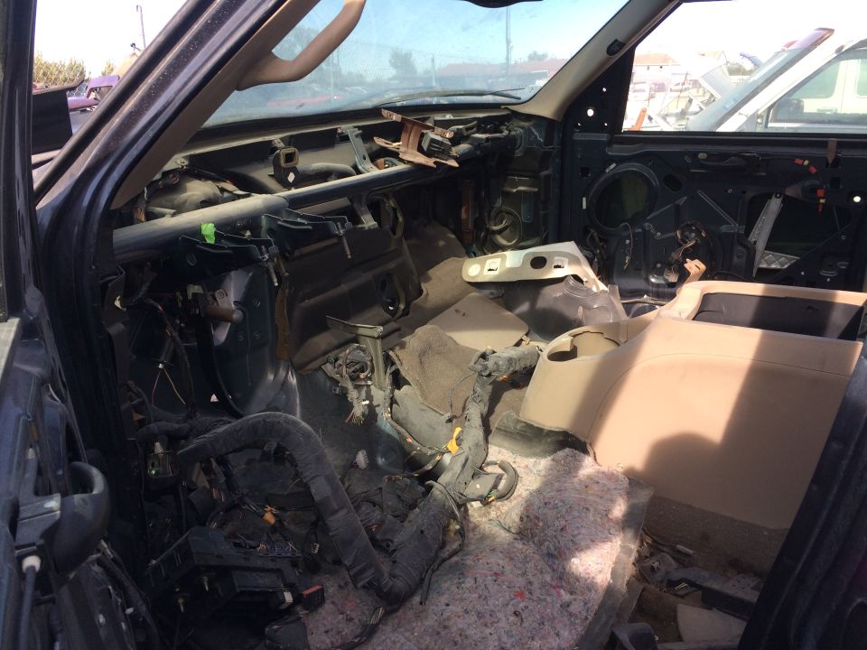 Dismantled vehicle interior showing exposed wiring, insulation, and dashboard components.