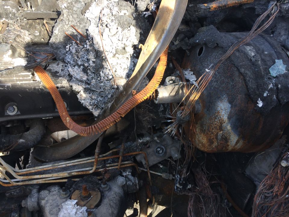 Burnt and damaged engine bay with melted hoses and wires.