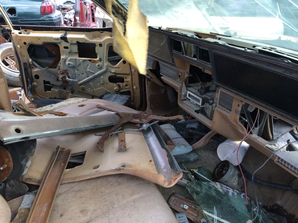 Interior of a dismantled car showing exposed door panel and dashboard with wires.