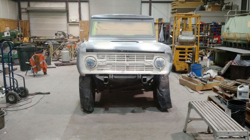 1971 Ford Bronco in primer gray, front view, in a workshop setting.