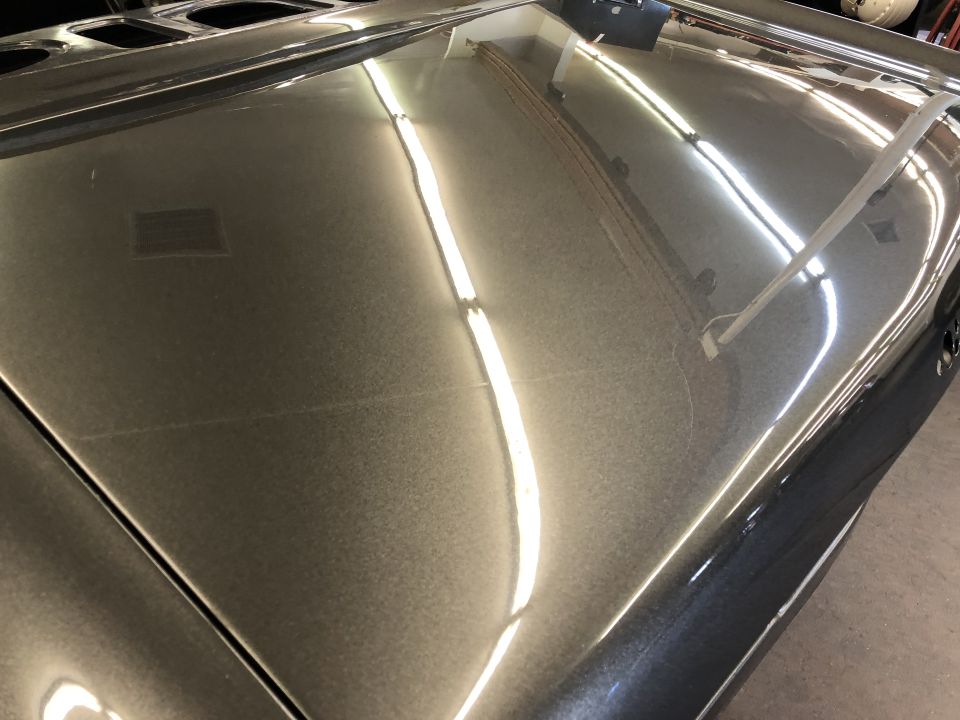 Metallic gray car hood with reflections, showing surface imperfections.