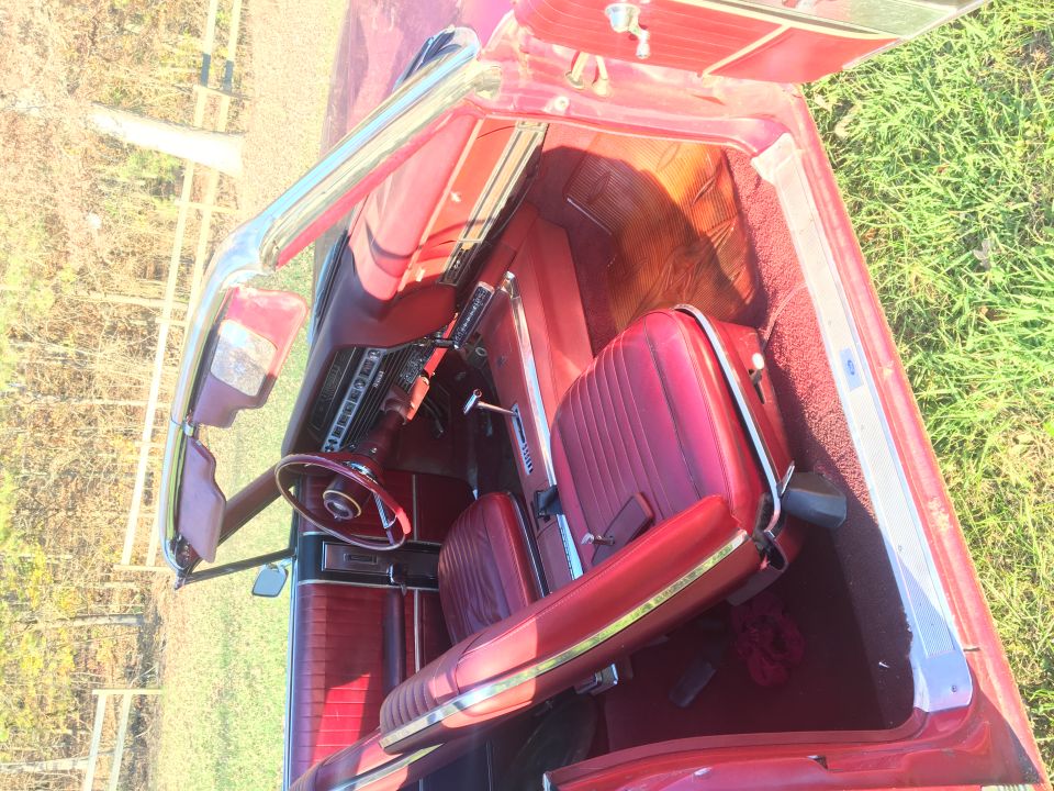 Interior of a vintage red convertible car, showing seats, dashboard, and steering wheel.