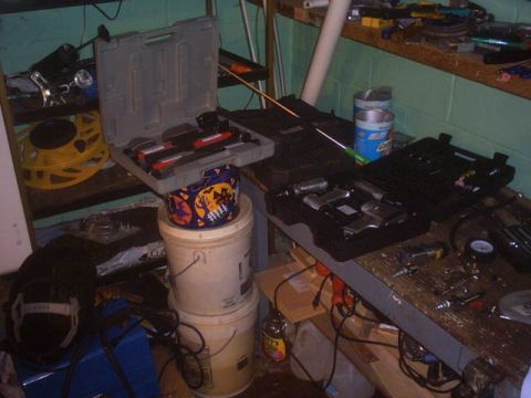 1991 Ford LTD Crown Victoria - A collection of air tools and toolboxes are organized on shelves and buckets in a workshop.