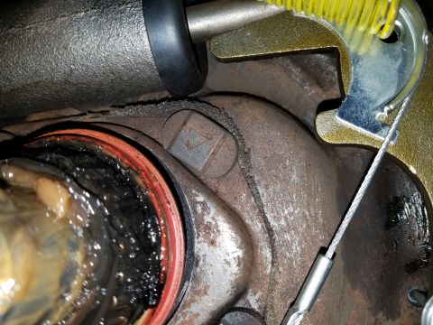 1971 Ford Mustang - A close-up view of a vehicle's brake drum assembly shows a rusted drum, a damaged red seal, and a metal cable attached to a brake shoe mech…