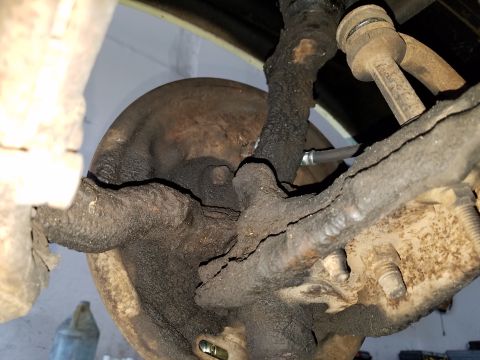 1971 Ford Mustang - This is a close-up, low-angle shot of the heavily greased and dirty suspension components of a classic car, likely a 1971 Ford Mustang. The…