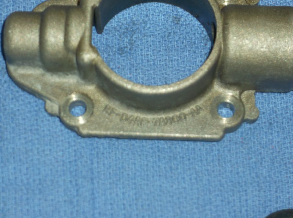 Metal automotive part with stamped text 'EF-D2AF-7A100-AA' and 'SUPERMOTORS www.supermotors.net'
