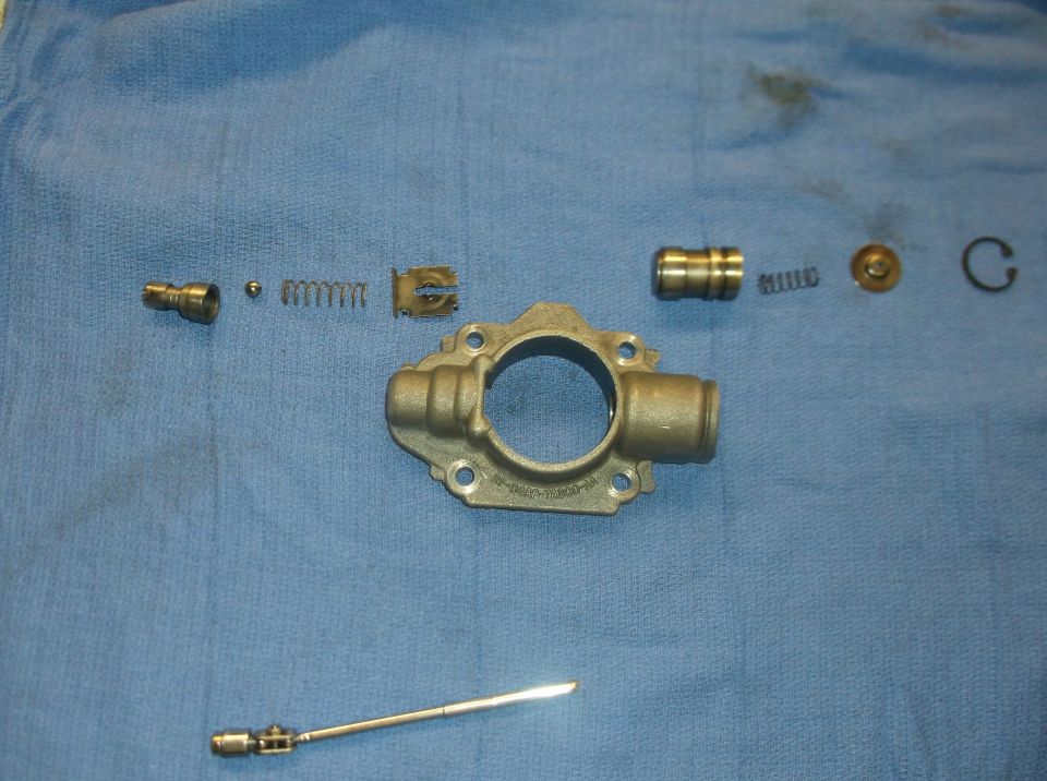 Disassembled oil pump parts laid out on blue cloth, including housing, springs, ball, and plunger