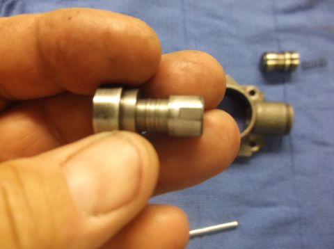1979 Ford Ranchero - Close-up of a hand holding a metal bolt and a mechanical part.