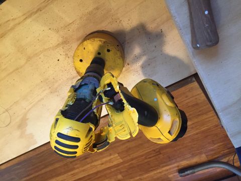 1967 Ford Custom Wagon - A yellow power tool, possibly a drill, with a large hole saw attachment is shown on a wooden surface. The tool appears damaged.
