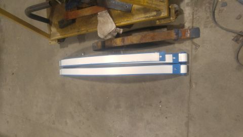 1971 Ford Bronco - Two white and blue metal bars are shown on a concrete floor, possibly parts for a larger assembly.