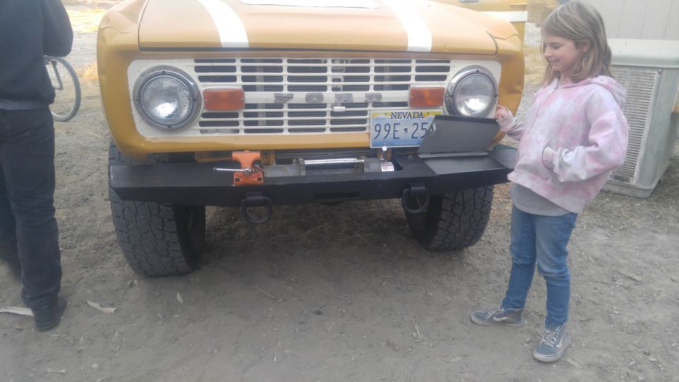 Yellow 1971 Ford Bronco front end with a girl standing next to it