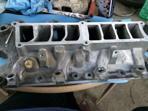 1989 Ford Bronco - An engine intake manifold is shown, with visible casting marks and ports, suggesting it is a component from a larger engine assembly.