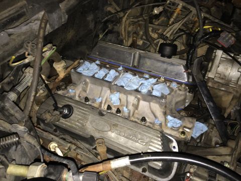 1989 Ford Bronco - The intake manifold is off the engine, exposing the cylinder heads and ports, with paper towels stuffed into the openings.