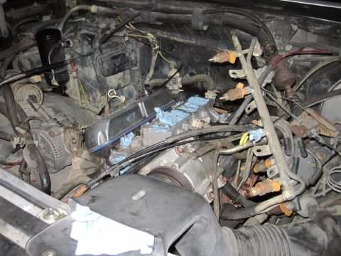 1989 Ford Bronco - Engine bay components are visible, including fuel injectors and an alternator, with blue rags protecting the cylinders.