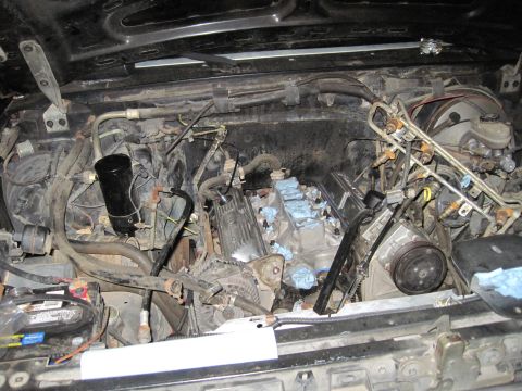 1989 Ford Bronco - The engine bay shows a V8 engine undergoing work, with fuel injectors and other components exposed.