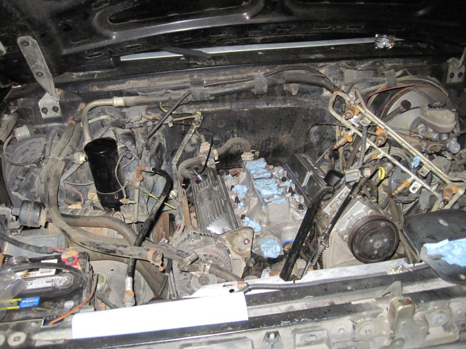 Engine bay with V8 engine partially disassembled, fuel injectors visible
