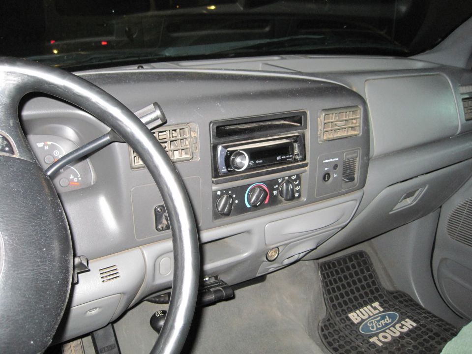 Dashboard of a Ford truck with aftermarket stereo and "Built Ford Tough" floor mat