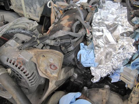 1989 Ford Bronco - Engine bay components including alternator and wiring, partially covered with aluminum foil and blue rags.