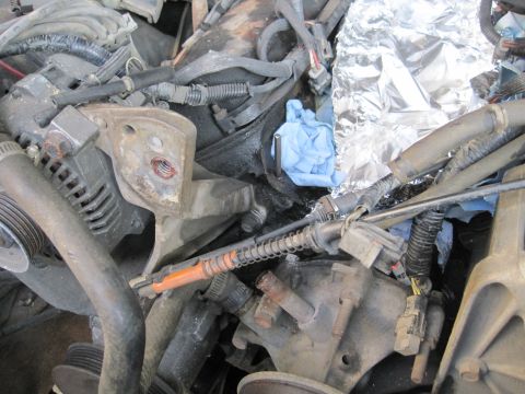 1989 Ford Bronco - Engine bay details with various components and a blue glove wrapped in foil.