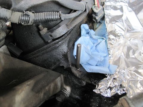 1989 Ford Bronco - A hex wrench is shown inserted into an engine component, partially covered by a blue shop towel and aluminum foil.