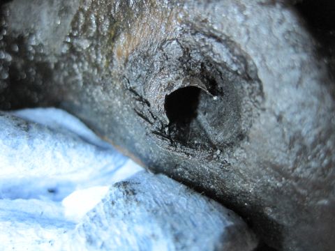 1989 Ford Bronco - This damaged metal component shows significant corrosion and a hole, suggesting wear or impact.