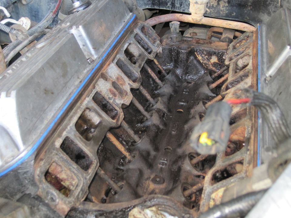 Close-up of a dirty engine intake manifold with visible rust and oil buildup