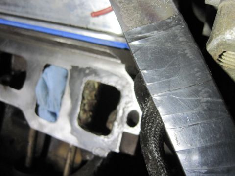 1989 Ford Bronco - Close-up view of an engine intake manifold, showing a port covered with a blue rag and blue tape on the surrounding metal.