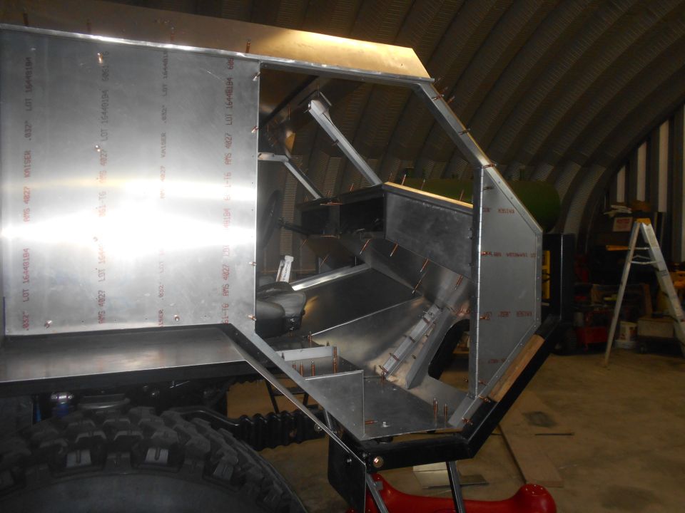 Aluminum panels being riveted to a frame, showing interior structure and a large tire