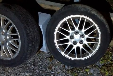 1994 Subaru Legacy - Close-up of two car wheels and tires, one a silver multi-spoke alloy rim.