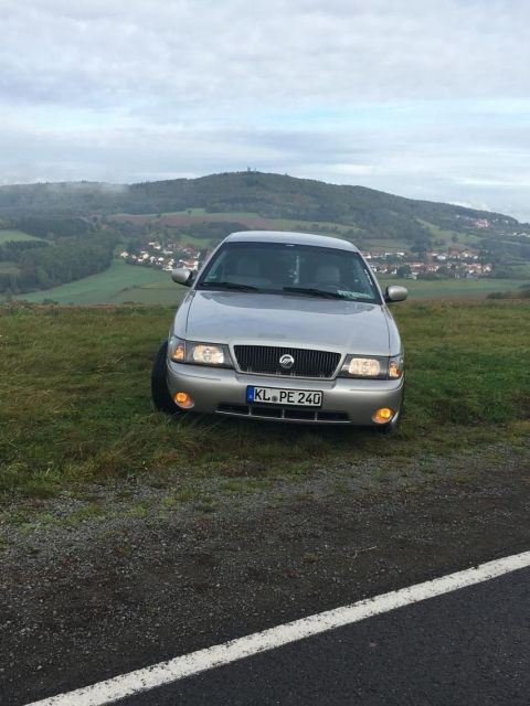 2003 Mercury Marauder - A silver 2003 Mercury Marauder is parked on a grassy hill overlooking a small town.