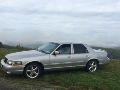 2003 Mercury Marauder - A silver 2003 Mercury Marauder is parked on a grassy incline under a cloudy sky.