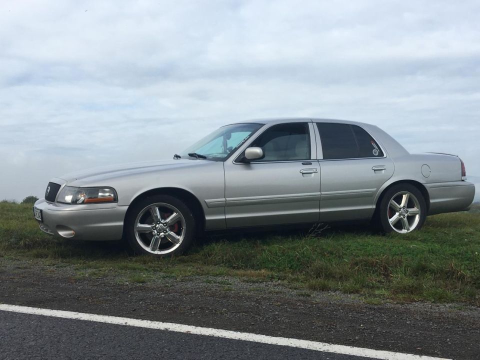Silver 2003 Mercury Marauder sedan parked on a grassy shoulder, side view