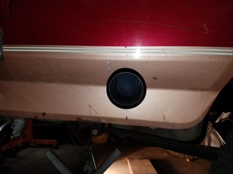1995 Ford Bronco - The rear side panel of a vehicle shows a circular exhaust pipe opening.
