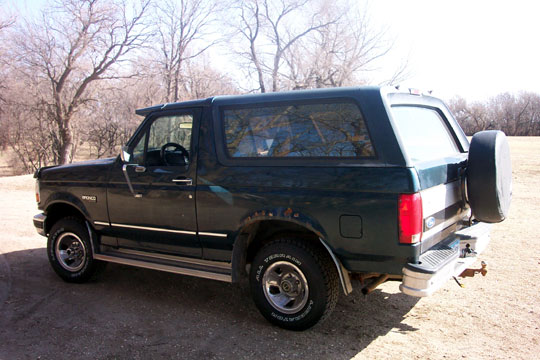 Dark green Ford Bronco, 1992 model year, with a spare tire mounted on the rear door and visible rust around the rear wheel well