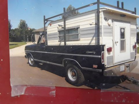 1994 Ford Bronco - This Ford pickup truck is equipped with a camper shell and a rack system, seen from the rear.