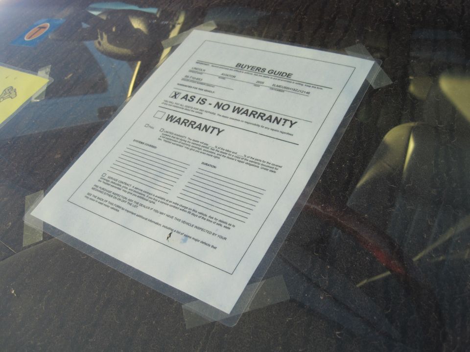 Buyers guide document taped to a car windshield, showing 'AS IS - NO WARRANTY'