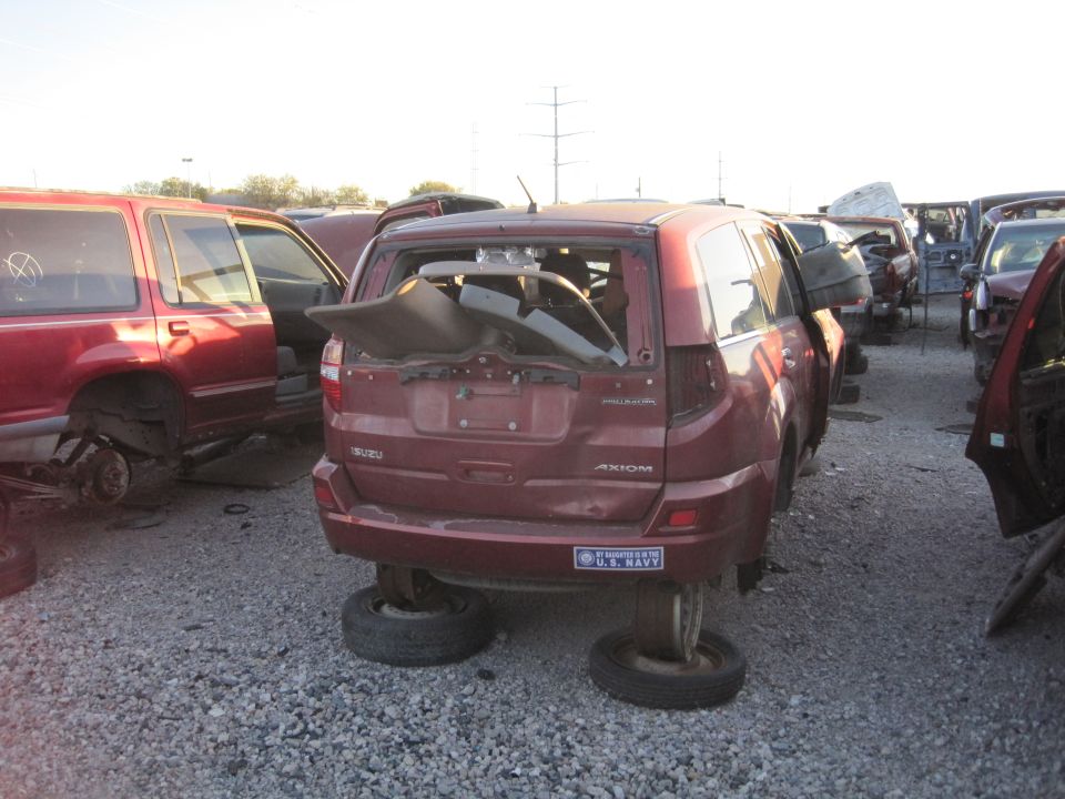 Maroon Isuzu Axiom SUV with broken rear window, missing tires, and a "U.S. Navy" sticker on the bumper