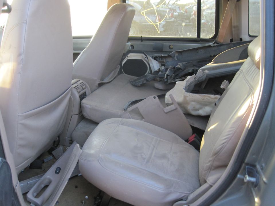 Interior of a car with torn-out parts and damaged seats. Looks like it's in a junkyard
