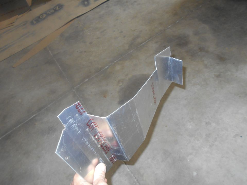 Metal bracket with red markings, held by a hand against a concrete floor