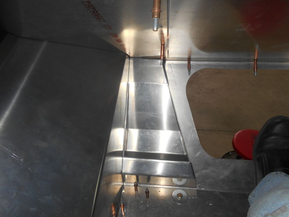 Close-up of metal paneling with rivets and copper fittings, some text visible on upper panel