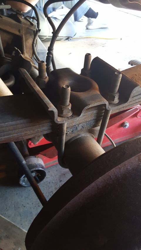 1996 Ford Bronco - Close-up of a vehicle's rear axle suspension hardware, showing a U-bolt securing a leaf spring.