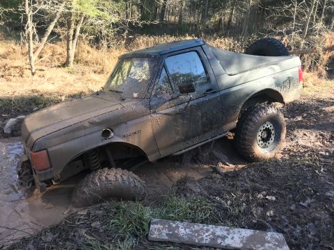 1989 Ford Bronco - Muddy 1989 Ford Bronco navigating an off-road trail and getting stuck in deep mud.