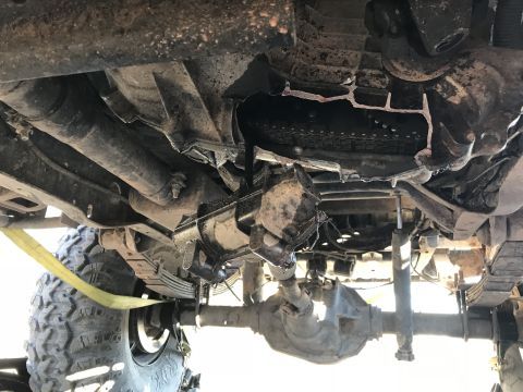 1989 Ford Bronco - The underside of a 4x4 vehicle shows a damaged drivetrain component and suspension system.