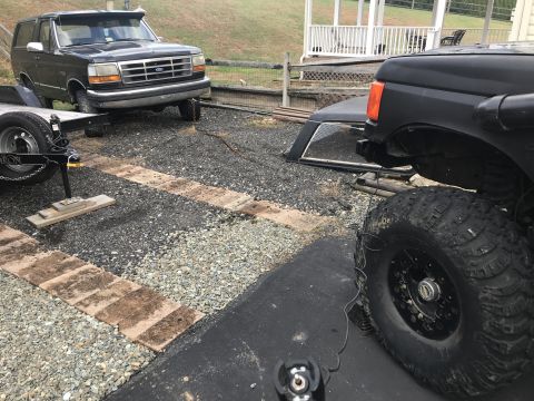 1989 Ford Bronco - A black Ford Bronco is parked next to a trailer, with another vehicle partially visible in the foreground.