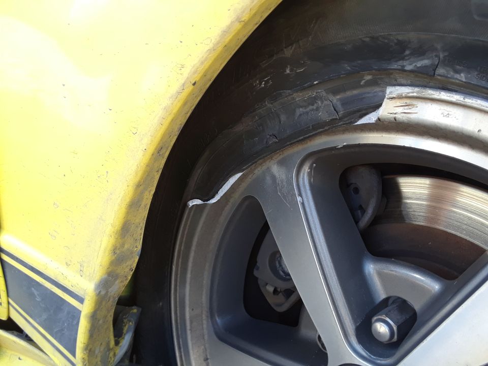 Yellow car fender with a damaged tire and rim
