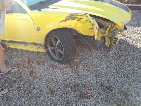 2003 Ford Mustang - Front passenger side of a yellow 2003 Ford Mustang showing collision damage.