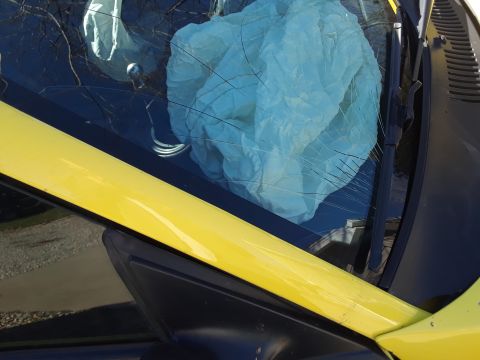 2003 Ford Mustang - The interior of a yellow vehicle shows a deployed airbag and a heavily cracked windshield.