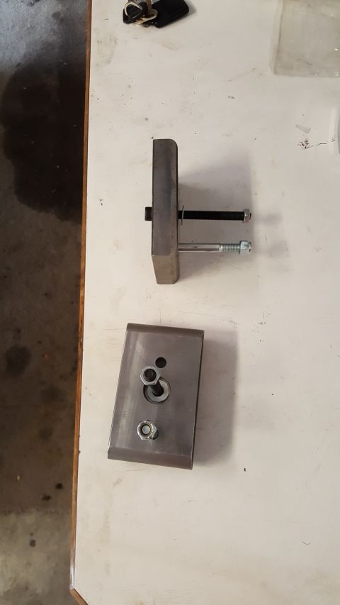 1996 Ford Bronco - A shackle flip kit, consisting of metal brackets and bolts, is laid out on a surface.