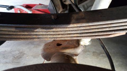 1996 Ford Bronco - Close-up view of vehicle suspension components, including leaf springs and a differential, with a red jack visible.