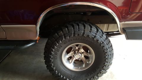 1996 Ford Bronco - The rear wheel and fender flare of a 1996 Ford Bronco are visible, a large off-road tire and chrome trim.
